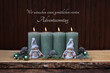 Adventsdekoration -Serie:  Vier brennende Kerze mit Zweigen und Weihnachtskugeln vor einem braunen Holzhintergrund. Mit der Beschriftung wir wünschen einen gemütlichen vierten Adventssonntag.
