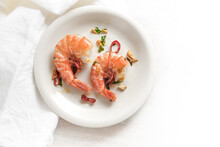 Two Fried Tiger Prawns Or Shrimps With Red Chili Pepper, Garlic And Herbs On A White Plate, Spicy Seafood Meal, High Angle View From Above, Copy Space