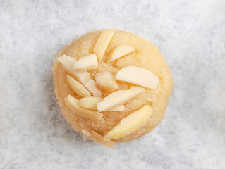 Gluten free almond flour cookie with almond slices on top. Close up of unbaked raw cookie dough. Round cookie dough balls with almond slices on parchment paper. GF almond cookies. Selective focus.