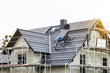 Workers installing solar panels on the roof of a single family house