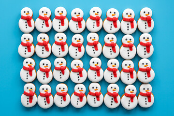 Wall Mural - Gingerbread snowmen covered with icing on a blue background, flat lay.