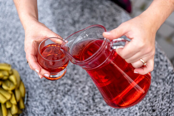 Woman pouring healthy cranberry juice from bottle into glass.