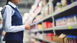 A grocery store manager reviewing inventory in the backroom, Grocery store, blurred background