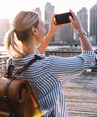Wall Mural - female tourist testing cellphone while taking photos of city