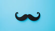 Black moustache on blue background with copy space. Movember campaign symbol. Prostate cancer awareness month.