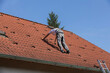 An unidentified man is preparing the roof for the installation of solar panels. the roof of a family house with red tiles,