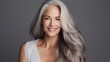 Beautiful woman with smooth healthy face skin. Gorgeous aging mature woman with long gray hair smiling for the camera. Beauty and cosmetics skincare advertising concept