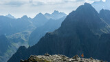 Fototapeta  - Tatry Wysokie, Rysy, zejście ze szczytu po stronie Słowackiej, w piękny letni dzień. Turystka z pomarańczowym plecakiem