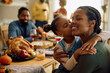 © Drazen - Grateful black girl kisses her mother during Thanksgiving family meal.