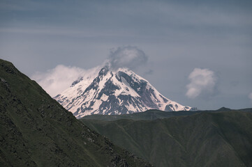 An Early morning view of a snowcapped Kazbegi Mountain with clouds surrounding it