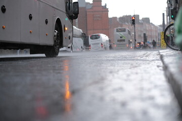 Low angle still image of the road during rainy day with cars and buses in the background in Dublin, Ireland