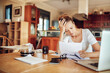 © Geber86 - Young woman going over her financials in the kitchen of her home