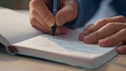 Wall Mural - Closeup businessman hands writing notes at desk. Man preparing schedule notebook