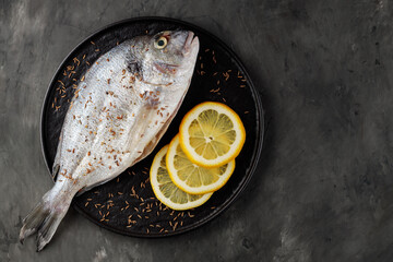 Wall Mural - Fresh raw dorado fish and lemon slices on dark background. Top view. Copy space