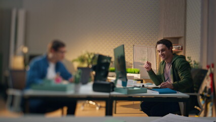 Wall Mural - Smiling coworkers talking together at computer table blur effect. Team working