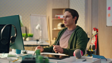 Wall Mural - Focused artist staring computer display in evening office. Serious man working