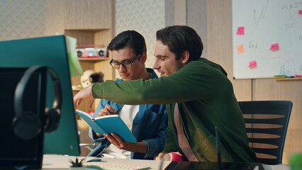 Wall Mural - Startup guys discussing notebook flipping pages at office. Team video call