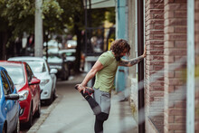 Young man stretching his legs before jogging in the city streets