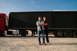 © phoenix021 - Father and son together starting trucking business, standing proudly in front of long hail truck with trailer