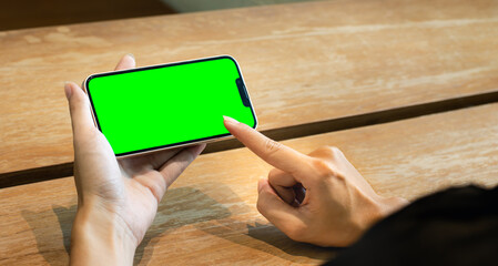 Poster - Woman using smartphone blank screen green background touching monitor. Technology and lifestyle.