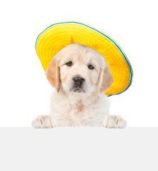 Wall Mural - Golden retriever puppy wearing sunglasses and summer hat looks above empty white banner. isolated on white background