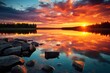 A beautiful sunset over a serene lake, with rocks in the foreground. 