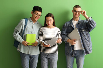 Canvas Print - Happy students with notebooks and laptop on green background