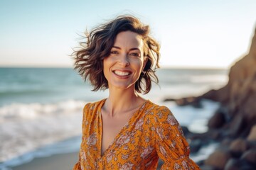 Portrait of a beautiful woman in orange dress smiling on the beach