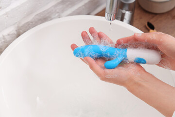 Wall Mural - Woman washing vibrator over sink, closeup