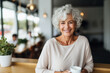 Portrait of smiling senior woman holding cup of coffee while sitting in cafe