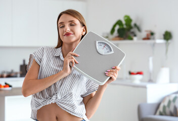 Canvas Print - Beautiful young woman with scales in kitchen. Weight loss concept