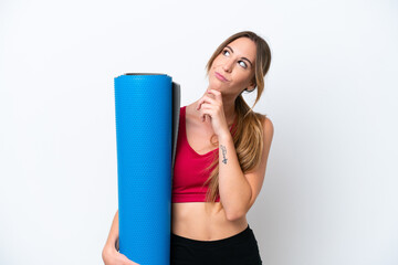 Wall Mural - Young sport woman going to yoga classes while holding a mat isolated on white background and looking up