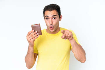 Wall Mural - Young caucasian man holding a wallet isolated on white background surprised and pointing front