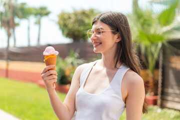 Wall Mural - Young pretty Ukrainian woman with a cornet ice cream at outdoors with happy expression