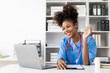 © MrAshi - Young African American woman in medical uniform working in clinic using computer at clinic Looking at laptop screen, having video conference with patient, online consultation concept.