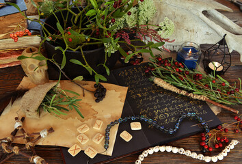 Wall Mural - Magic book of spells with runes and herbs on altar table. No foreign language, only fantasy symbols. Occult, esoteric and divination still life. Mystic Halloween background with vintage objects