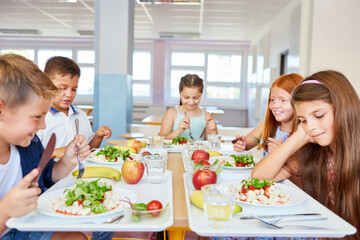 Wall Mural - Happy students eating food during lunch time in school cafe