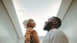 Bottom view of an African American male doctor wearing medical clothes talks to a child in a hospital corridor.
