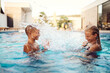 © Minet - In a sunlit modern villa, a young brother and sister joyfully splash and play in the pool, basking in the warmth of a perfect summer day