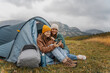 © olezzo - Young cheerful couple of lesbian girlfriends traveling with a tent. Hiking travel and trekking concept