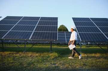 Portrait young indian technician or manager wearing formal cloths standing with solar panel. renewable energy, man standing crossed arm, copy space