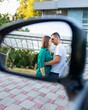 Young pretty caucasian couple kissing near an opened window of their car in review mirror reflection