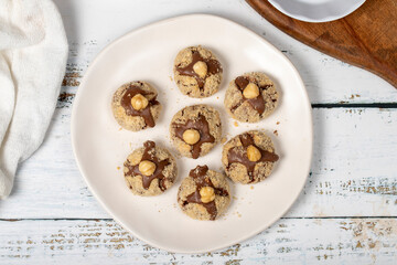 Wall Mural - Hazelnut cookies. Chocolate and hazelnut cookies on a white wooden background. patisserie products. Top view