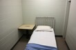 made bed in sparse detention cell, neat and tidy
