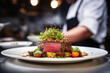 Close up of gorgeous meat dish in background of blurred chef making food in professional modern kitchen and bokeh lights. Working concept cooks and craftsmen.