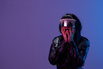 Wall Mural - Shocked pretty awesome brunet woman in leather jacket trendy specular sunglasses open mouth touch cheeks posing isolated in blue violet color light background. Neon party Cyberpunk concept. Copy space