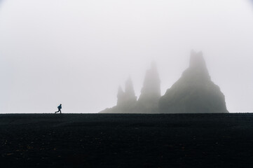 Photo of a runner running in stormy weather in Iceland with a mountain in a mist.