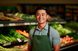 © Uliana - A handsome male supermarket worker on a background of fresh vegetables and fruits.