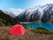 © Alex Sipeta - Camping with a red tent in the highlands on the shore of a beautiful lake. Panoramic views of snow-capped peaks and turquoise lake
