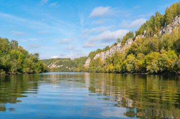 Wall Mural - autumn landscape, view of the high rocky bank of the sylva river, mirror image in the water.